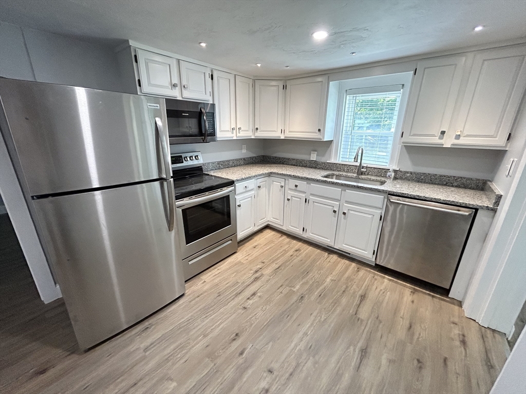 13 Maranook Road Worcester, MA 01606 - Photo 19 of 24 a kitchen with wooden floors white cabinets and stainless steel appliances