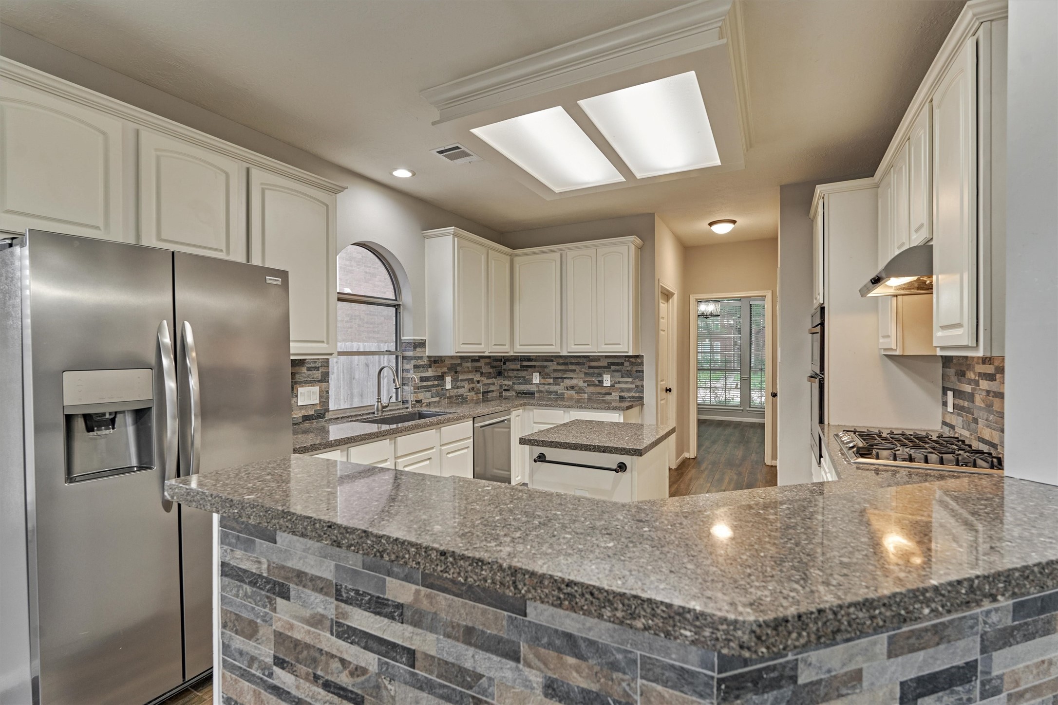 1618 Calmar Drive Spring, TX 77386 - Photo 12 of 30 a kitchen with stainless steel appliances granite countertop a refrigerator a stove and white cabinets with wooden floor