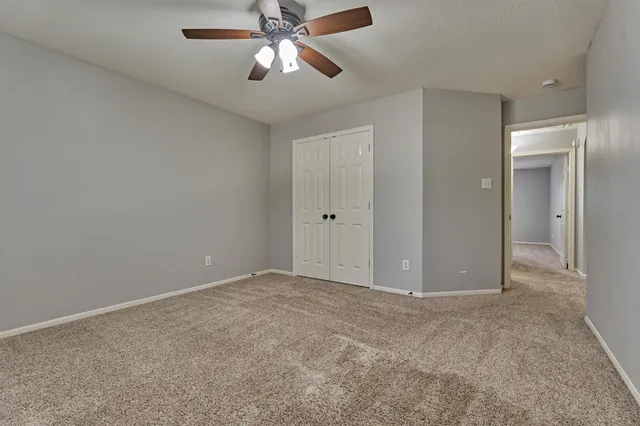 an empty room with closet and a chandelier fan
