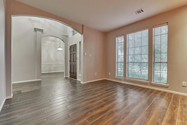 a view of an empty room with wooden floor and a window