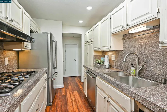 a kitchen with stainless steel appliances granite countertop a sink stove refrigerator and cabinets