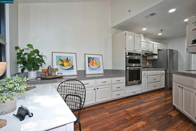 a kitchen with stainless steel appliances kitchen island granite countertop a stove a sink and a refrigerator