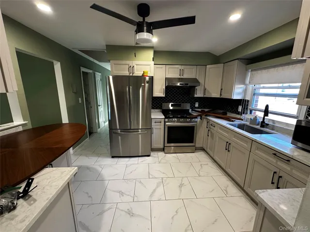 a kitchen with stainless steel appliances granite countertop a sink a stove a refrigerator a washer dryer and a dining table