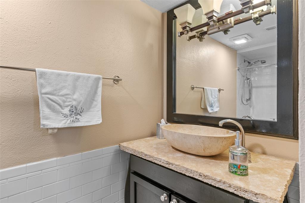 5904 Sandhurst Lane, Unit 147 Dallas, TX 75206 - Photo 16 of 19 a bathroom with a granite countertop sink a mirror and shower