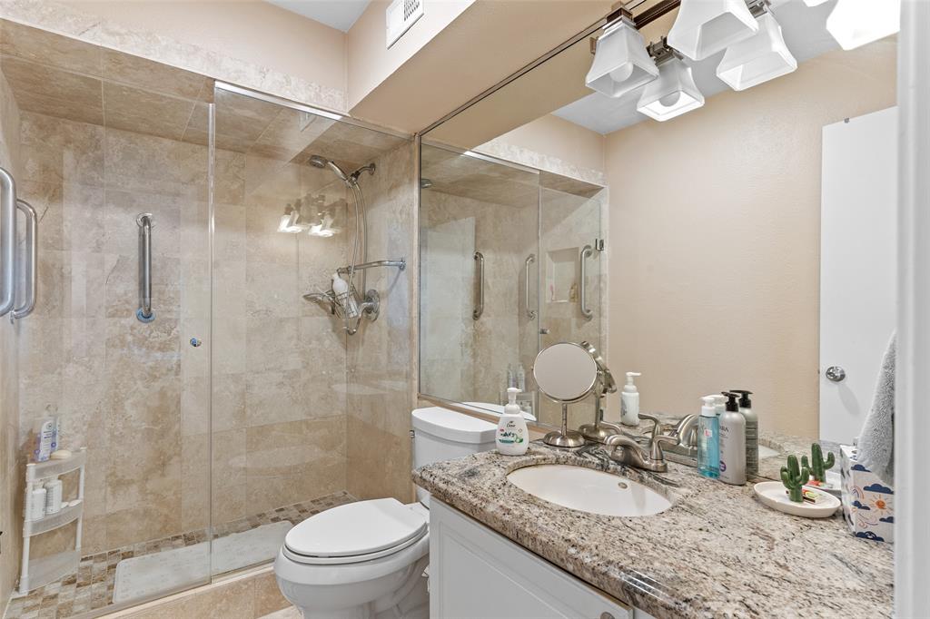 5904 Sandhurst Lane, Unit 147 Dallas, TX 75206 - Photo 10 of 19 a bathroom with a granite countertop sink a toilet a mirror and shower