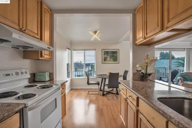 a kitchen with granite countertop a stove a sink a refrigerator dining table and chairs