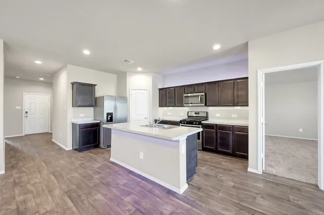 a large kitchen with stainless steel appliances kitchen island granite countertop a stove and a sink
