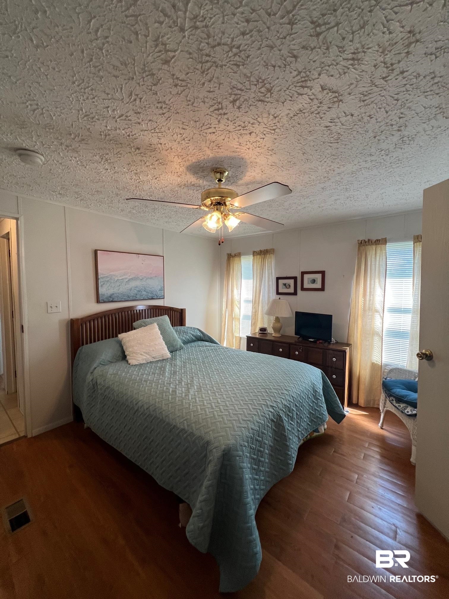1936 Ridgewood Drive Lillian, AL 36549 - Photo 5 of 30 Bedroom featuring visible vents, ceiling fan, a textured ceiling, and wood finished floors