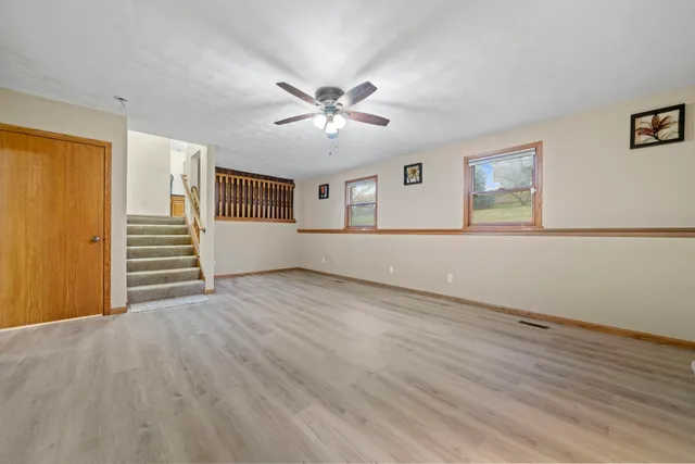 a view of an empty room with a window and wooden floor