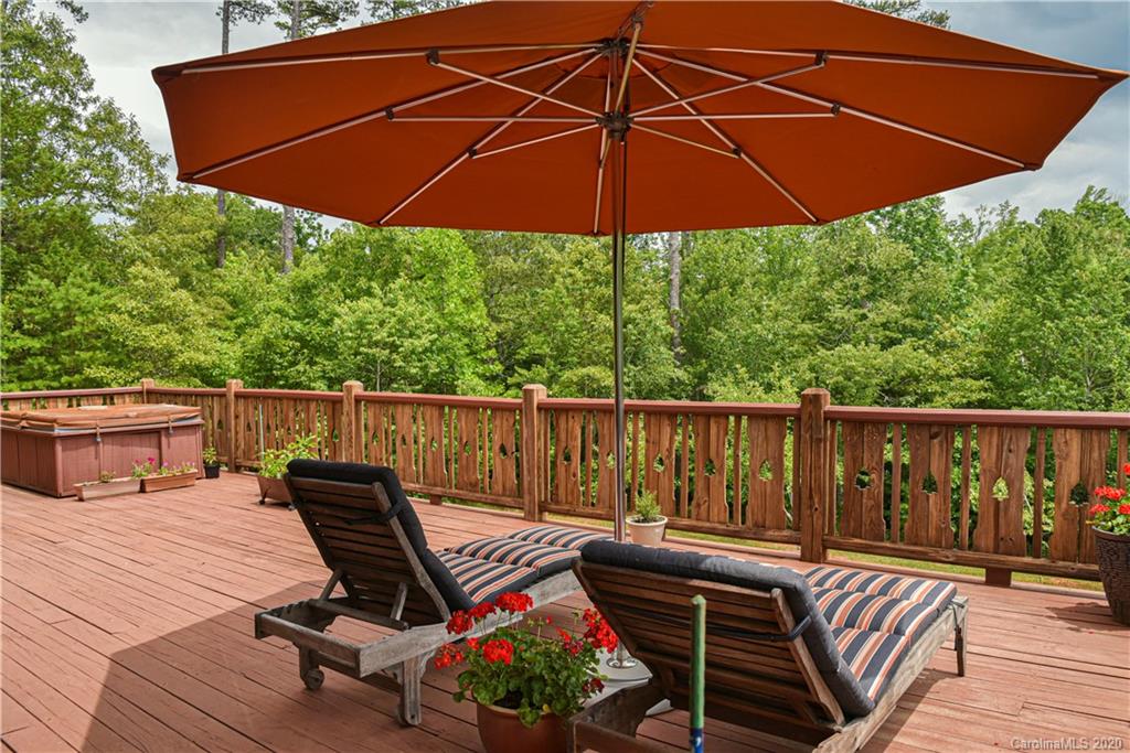 359 Dark Corner Road Rutherfordton, NC 28139 - Photo 11 of 36 a patio with wooden floor a yard a table and chairs under an umbrella