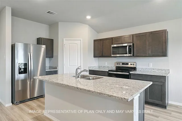 a kitchen with granite countertop a refrigerator and a sink