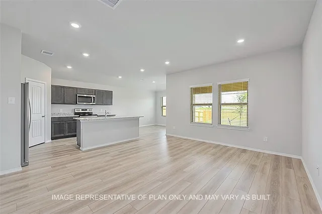 a large kitchen with kitchen island a sink dishwasher a stove and a refrigerator with wooden floor