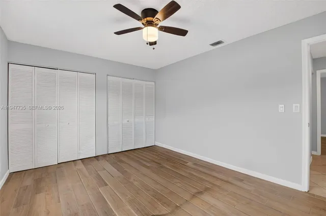 an empty room with wooden floor and a ceiling fan