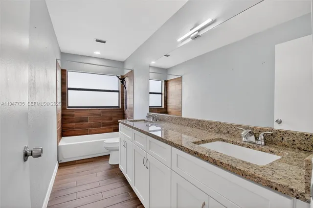a bathroom with a granite countertop sink and a large mirror