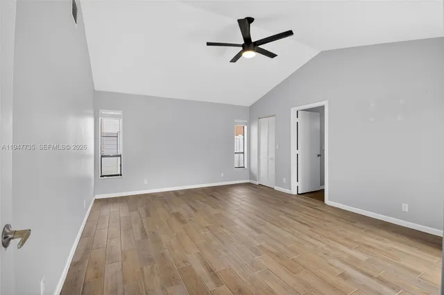 an empty room with wooden floor and windows