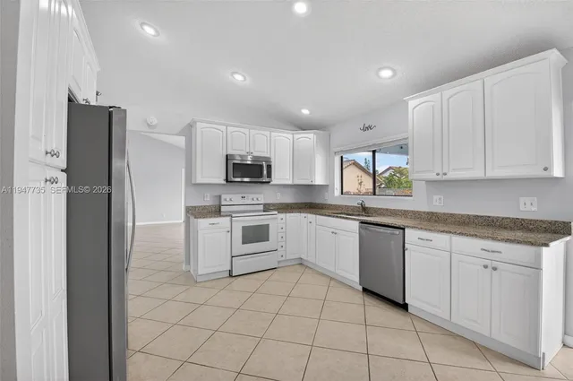 a kitchen with white cabinets stainless steel appliances and a window