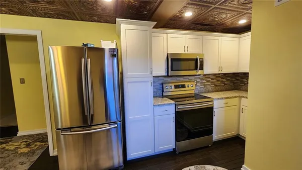 a kitchen with stainless steel appliances granite countertop a refrigerator and a stove top oven