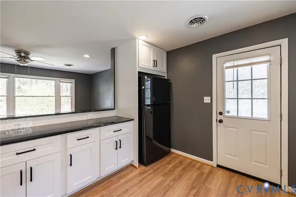 a kitchen with granite countertop white cabinets and refrigerator