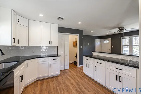 a large kitchen with stainless steel appliances granite countertop a lot of counter space and wooden floors