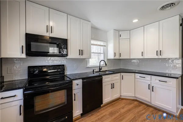 a kitchen with granite countertop a stove top oven a sink dishwasher and cabinets with wooden floor