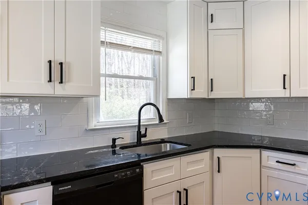 a kitchen with granite countertop white cabinets and a sink