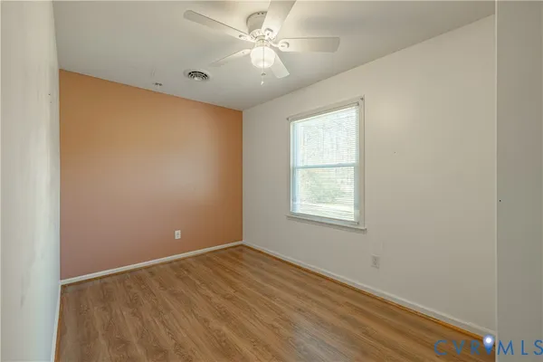 an empty room with a window and a ceiling fan