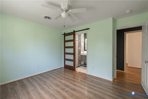 an empty room with wooden floor chandelier fan and windows