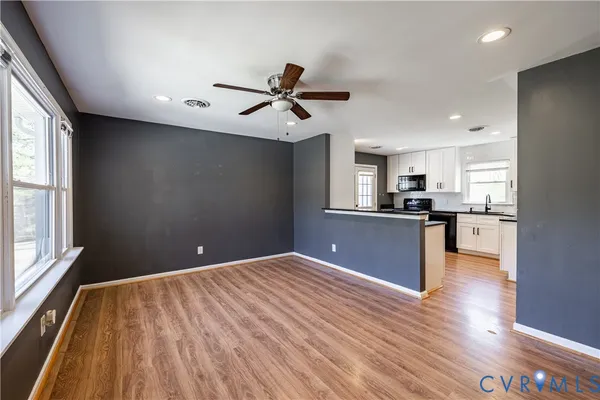 a view of kitchen and empty room with wooden floor and windows