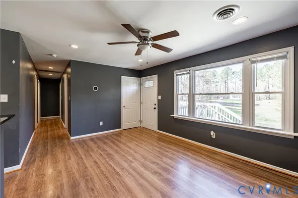 a view of an empty room with a window and wooden floor