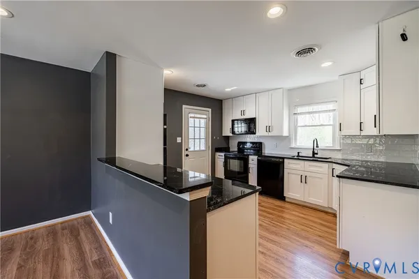 a kitchen with granite countertop a refrigerator stove top oven and sink