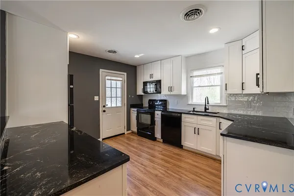 a kitchen with granite countertop a sink a counter top space and stainless steel appliances