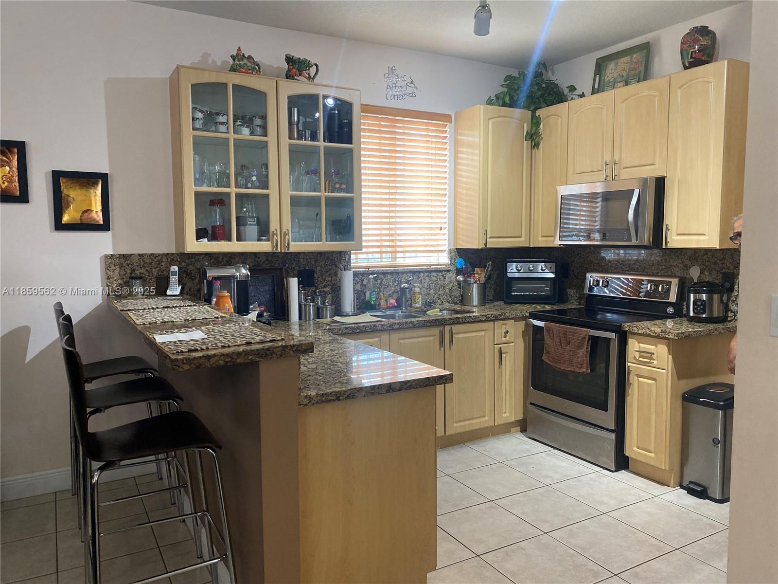 7760 Northwest 163rd Street Miami Lakes, FL 33016 - Photo 20 of 68 a kitchen with stainless steel appliances granite countertop a stove a sink and a microwave