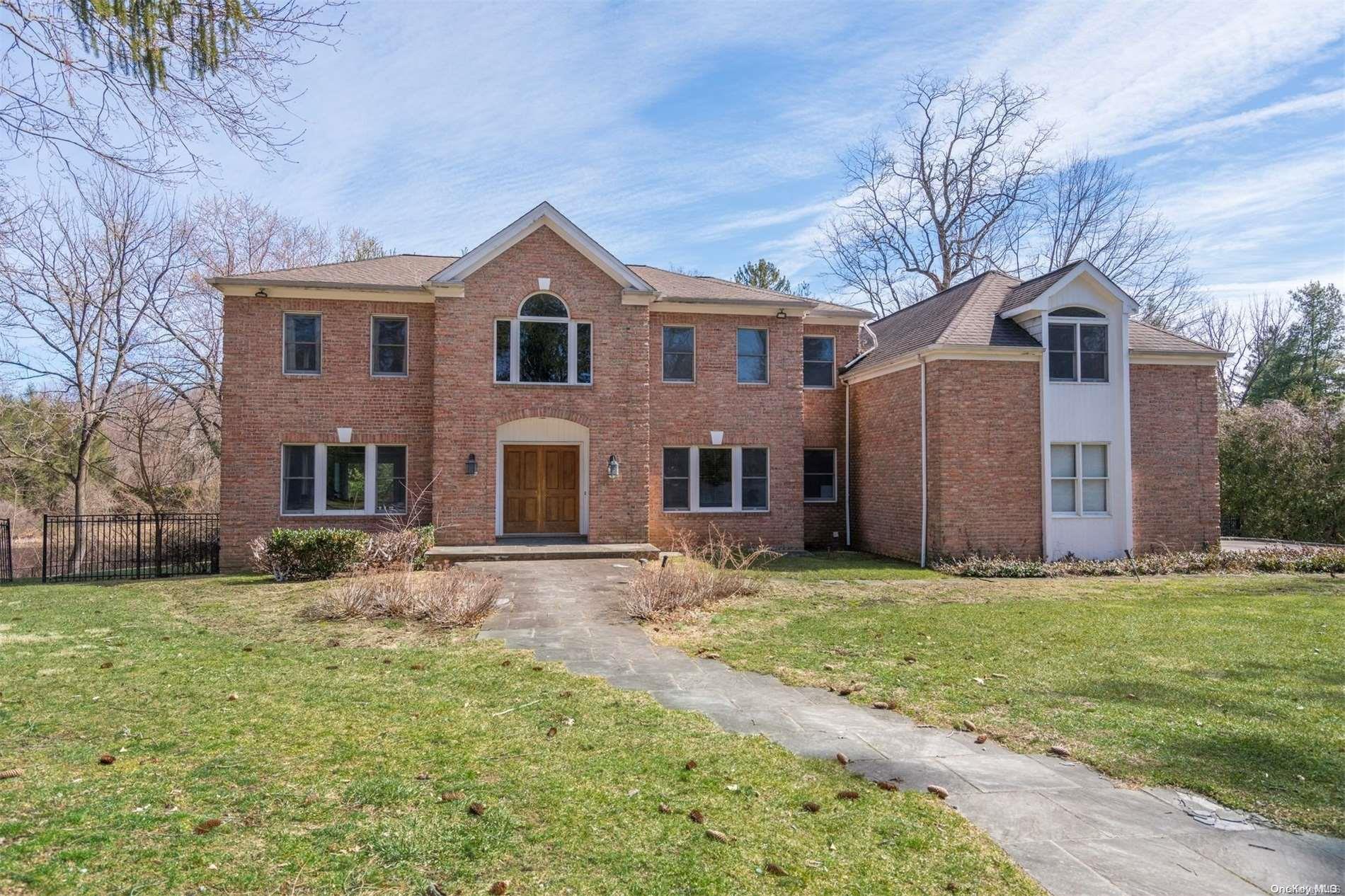 a view of a yard in front of a brick house with large windows