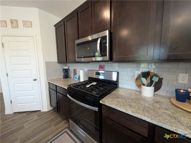 a kitchen with stainless steel appliances granite countertop a stove a sink and a microwave