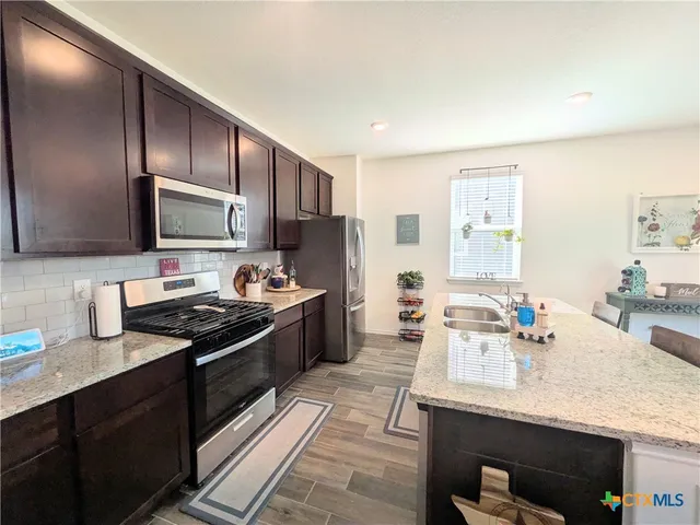 a kitchen with stainless steel appliances granite countertop a sink stove and refrigerator