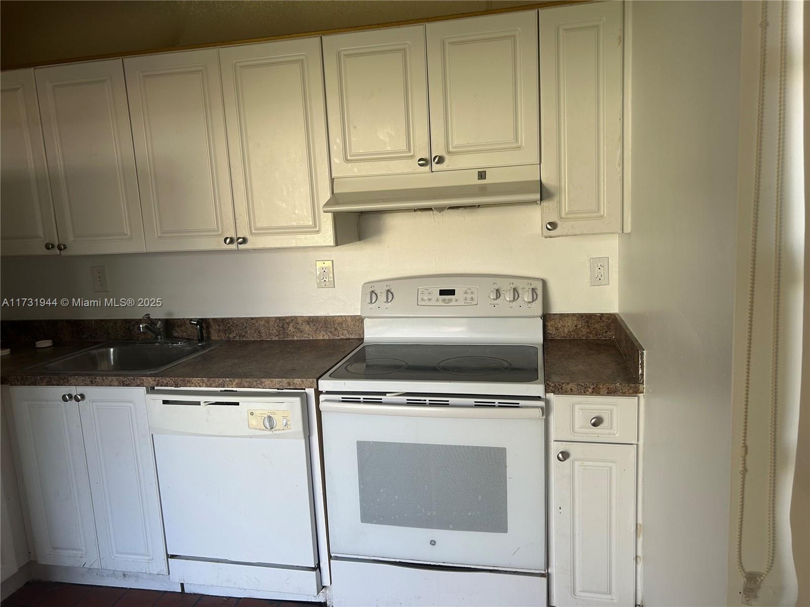Ives Estates Miami, FL 33179 - Photo 14 of 19 a kitchen with a stove and white cabinets