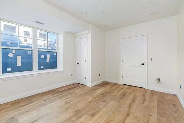 a view of an empty room with wooden floor and a window
