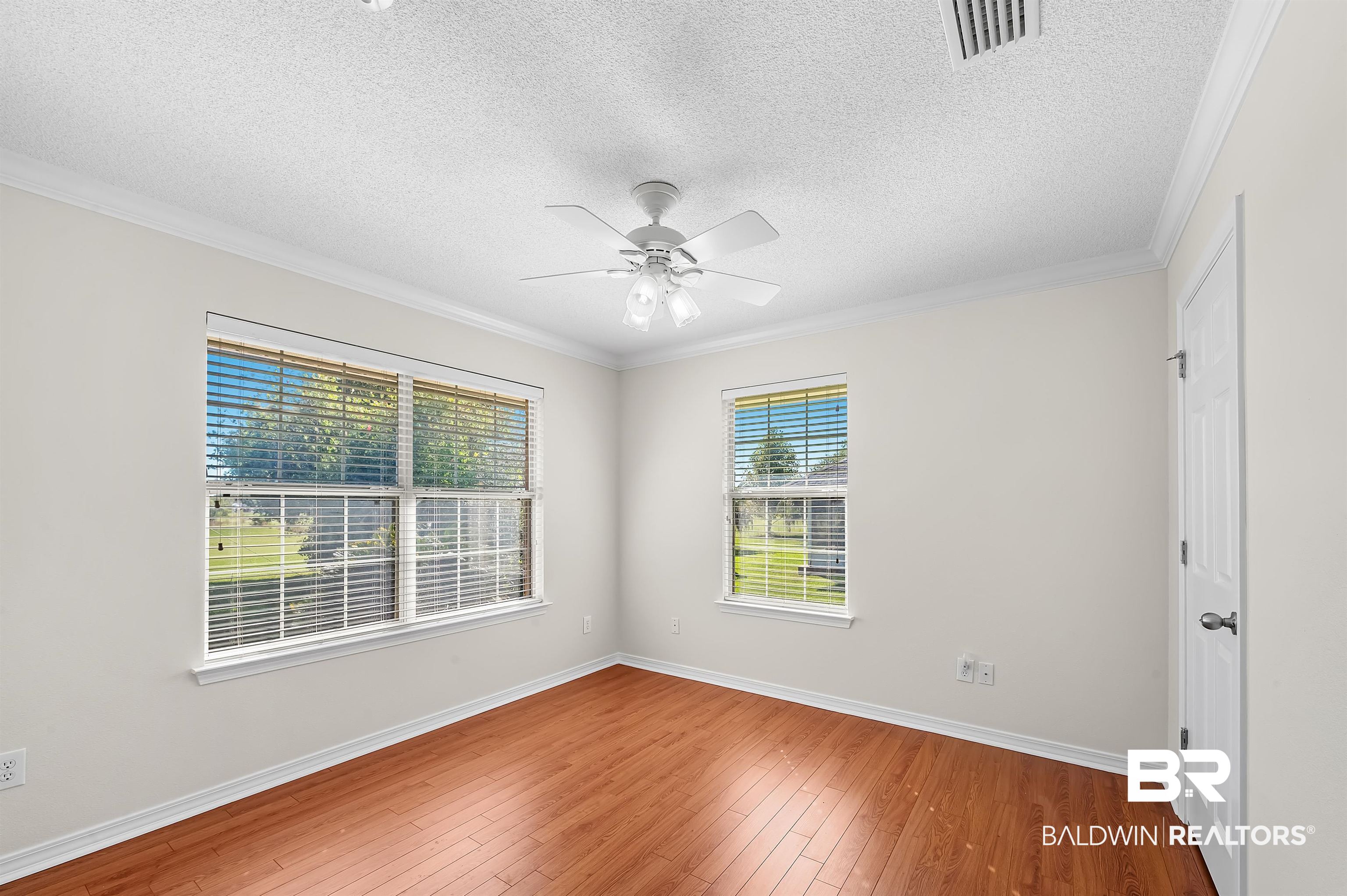 421 Collinwood Loop Foley, AL 36535 - Photo 41 of 62 Empty room featuring ceiling fan, a healthy amount of sunlight, wood-type flooring, and a textured ceiling