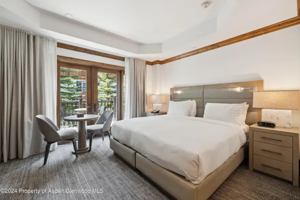 a large white bed sitting in a bedroom next to a window
