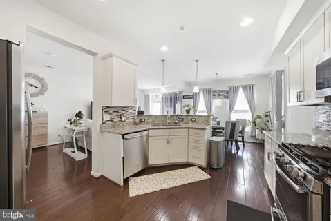 a kitchen with a sink cabinets stainless steel appliances and wooden floor