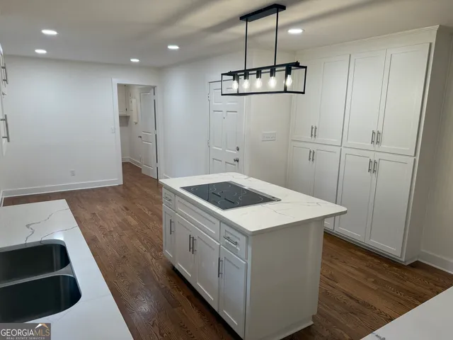a kitchen with a stove a sink a window and wooden floor