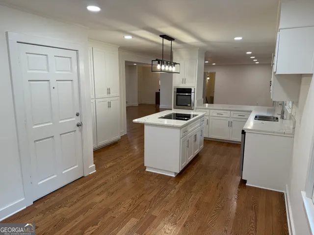 a kitchen that has a microwave a stove and wooden floor