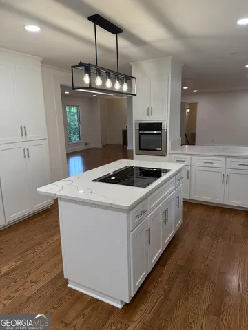 a kitchen with stainless steel appliances white cabinets and a wooden floor