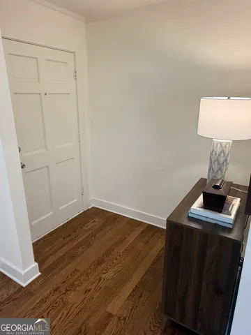 a view of an empty room with wooden floor and kitchen