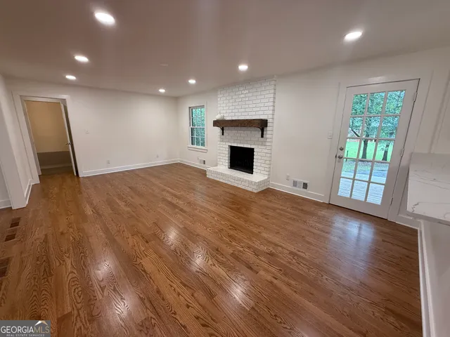 a view of empty room with wooden floor and fireplace