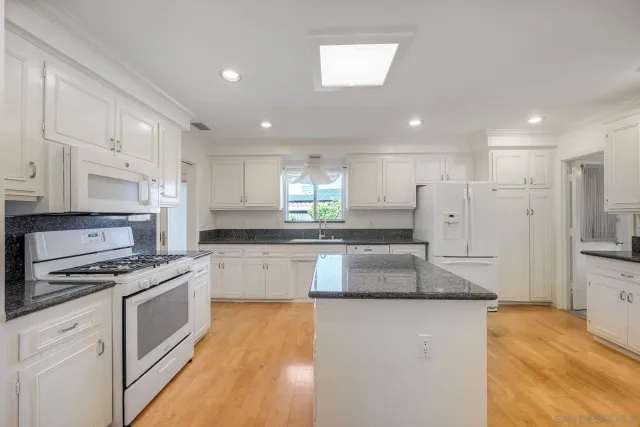 a large kitchen with granite countertop a large counter top stainless steel appliances and cabinets