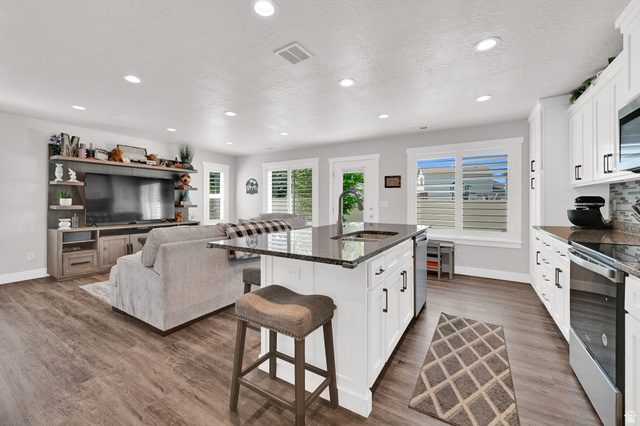 2777 West 4175th Street South, Unit 232 Roy, UT 84067 - Photo 11 of 27 Open-concept living space/kitchen featuring LVP flooring, recessed lighting, and white plantation shutters