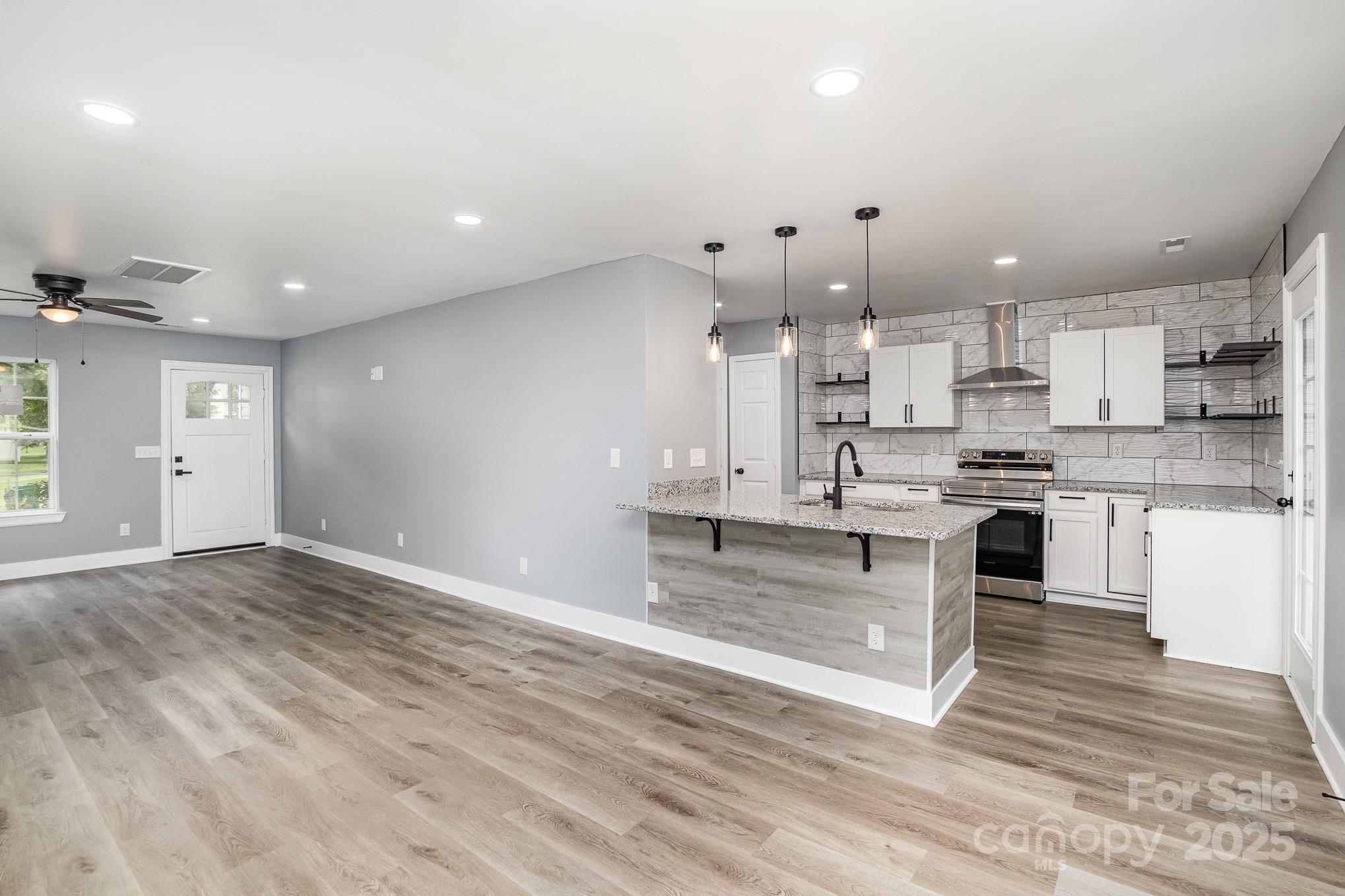 938 Valley Ridge Road Charlotte, NC 28214 - Photo 4 of 22 a large kitchen with stainless steel appliances kitchen island granite countertop a stove a sink and white cabinets