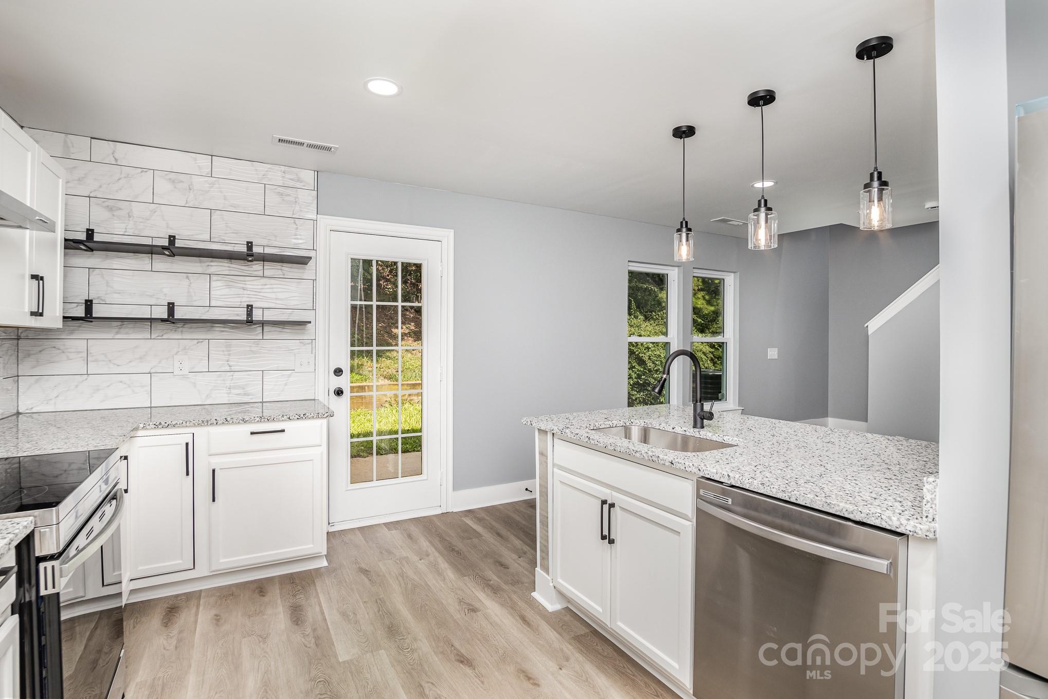 938 Valley Ridge Road Charlotte, NC 28214 - Photo 7 of 22 a kitchen with stainless steel appliances granite countertop a stove a sink and white cabinets with wooden floor