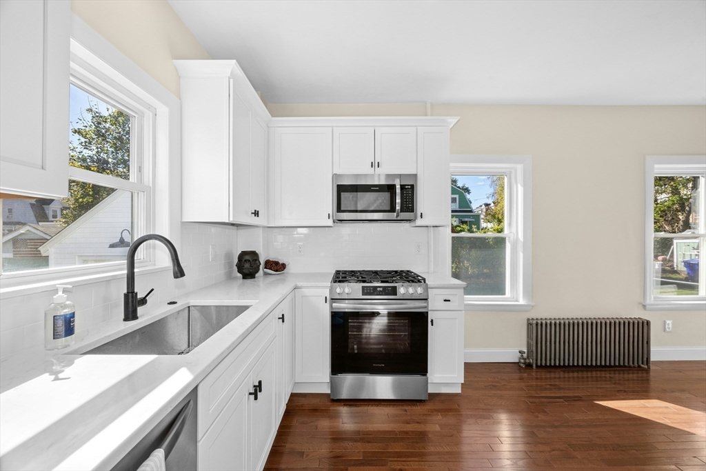 15 Arthur Street, Unit 15 Maynard, MA 01754 - Photo 7 of 21 a kitchen with stainless steel appliances granite countertop a sink a stove a microwave a window and white cabinets